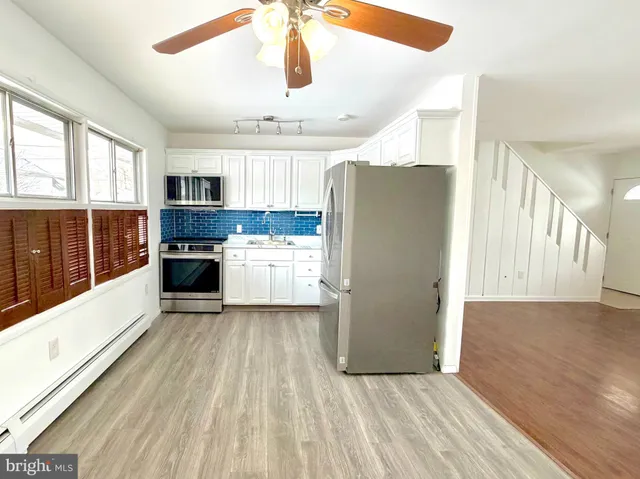 a kitchen with stainless steel appliances granite countertop a refrigerator a stove and a wooden floors