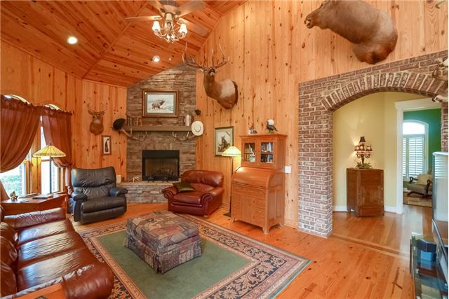 2090 Cairo Bend Road Lebanon, TN 37087 - Photo 17 of 20 Den with stacked stone gas fireplace, wood walls and ceilings as well as brick ached entry way into kitchen and hallway.
