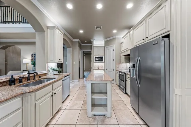 a large kitchen with stainless steel appliances kitchen island granite countertop a refrigerator and a sink