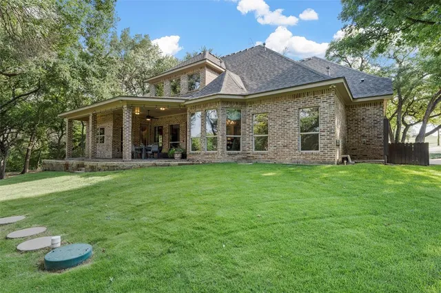 a view of a big house with a big yard and large trees