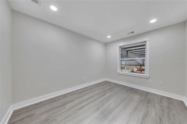 a view of an empty room with a window and wooden floor