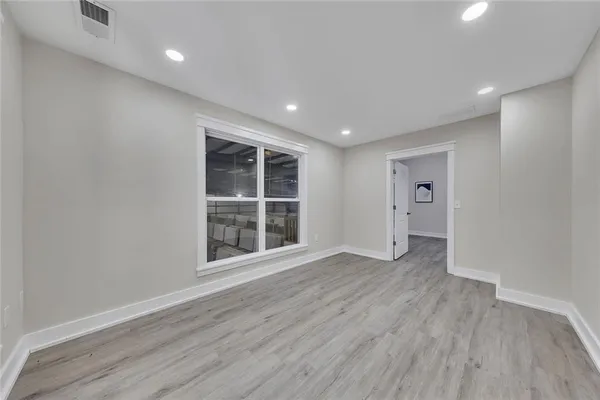a view of empty room with wooden floor and windows