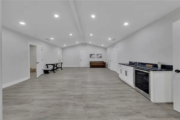 a living room with stainless steel appliances furniture a kitchen view and a wooden floor