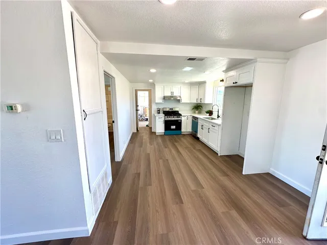 a view of a kitchen with a sink refrigerator and wooden floor