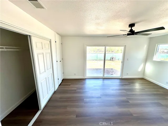 an empty room with wooden floor fan and windows