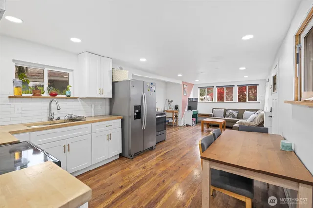 a large white kitchen with wooden floor a sink stainless steel appliances and cabinets