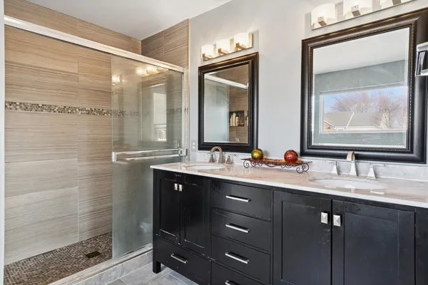 a bathroom with a double vanity sink mirror and shower