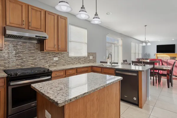 a kitchen with stainless steel appliances granite countertop a sink a stove and a wooden cabinets