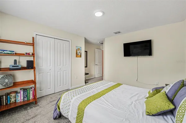 a bedroom with a bed a flat screen tv and a book shelf