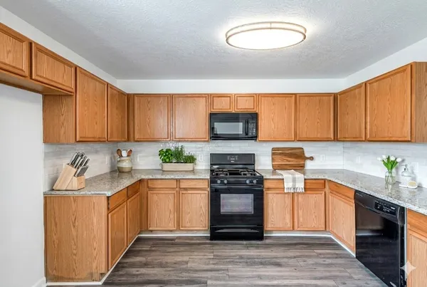 a kitchen with stainless steel appliances granite countertop a sink a stove a refrigerator cabinets and a window