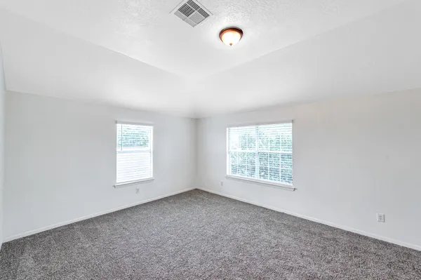 an empty room with windows and fan