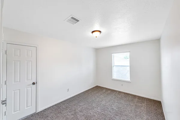 an empty room with windows and fan