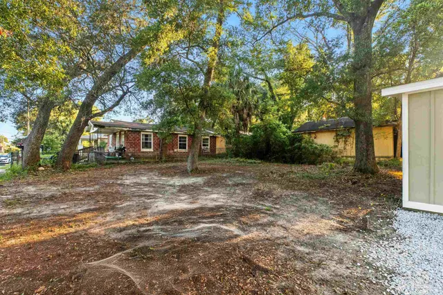 a view of a house with backyard and tree