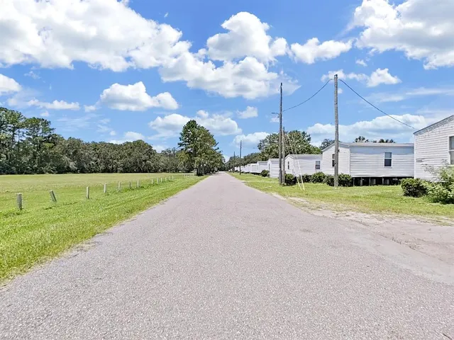 a view of a house with a big yard and a large trees