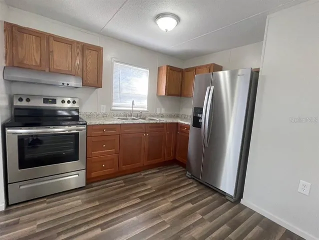 a kitchen with stainless steel appliances granite countertop a refrigerator stove and sink