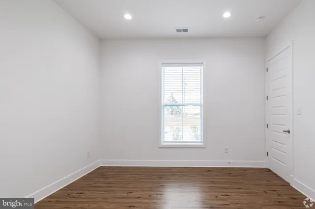 an empty room with wooden floor and window