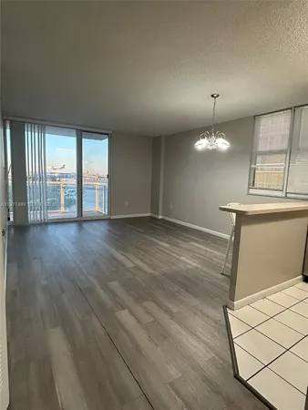an empty room with wooden floor chandelier and windows