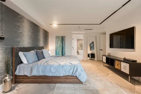 a spacious bedroom with a bed and a flat screen tv