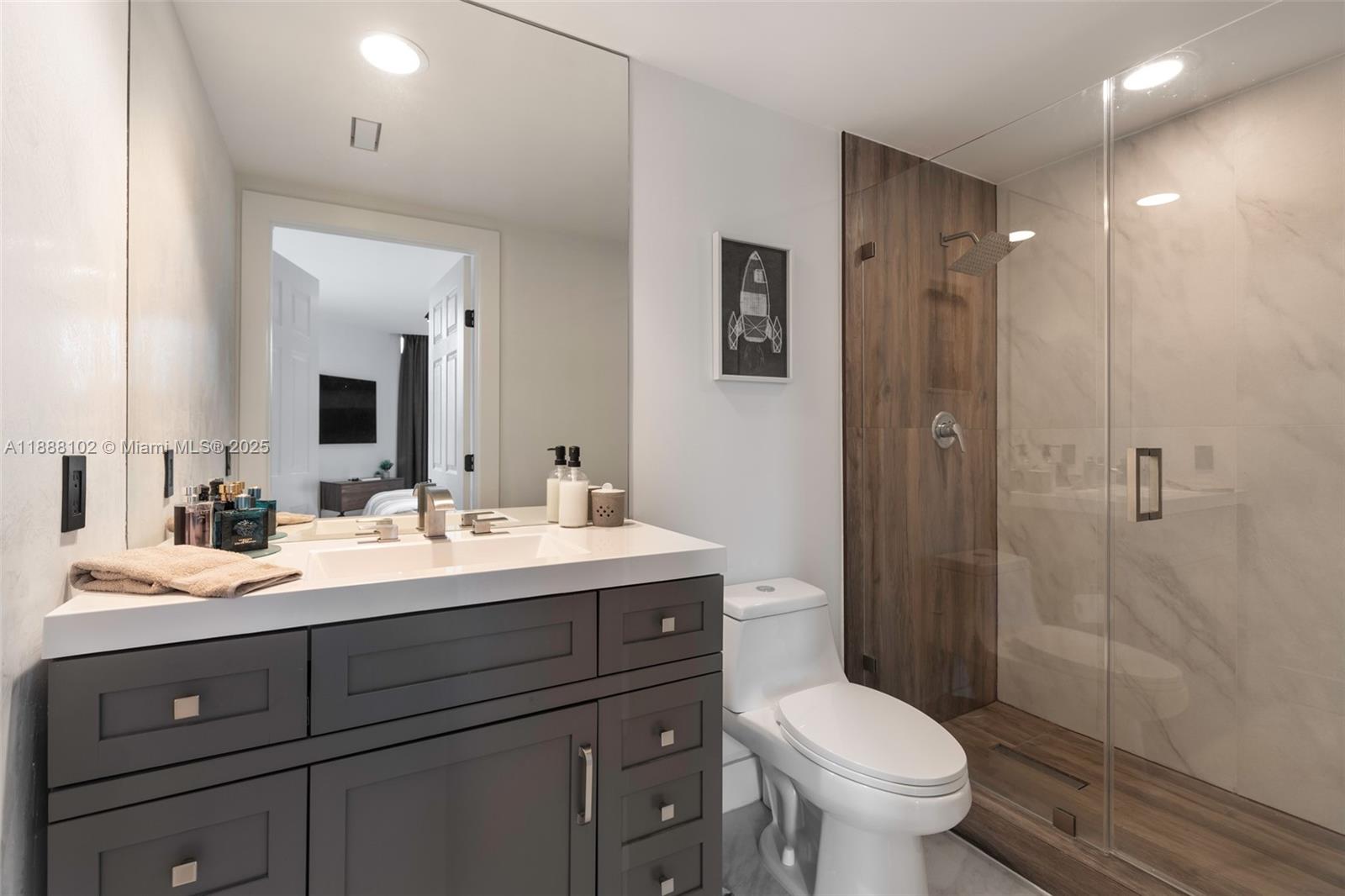 3370 Hidden Bay Drive, Unit 409 Aventura, FL 33180 - Photo 17 of 20 a bathroom with a toilet sink double vanity and mirror