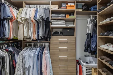 a view of walk in closet with clothes and shoes