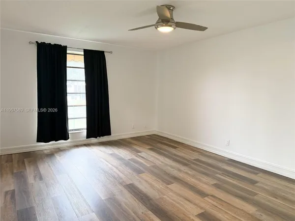 an empty room with wooden floor closet and windows