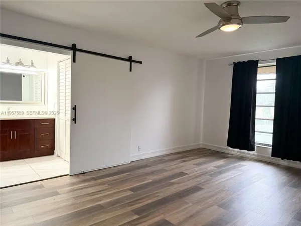 a view of an empty room with window and wooden floor