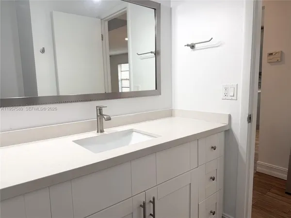 a view of a hallway with wooden floor and a bathroom