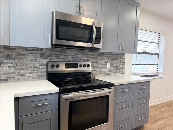 a kitchen with granite countertop a stove microwave and sink