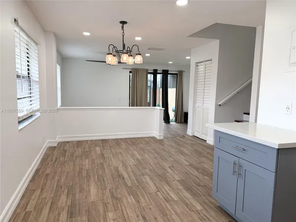 a view of an empty room with wooden floor and chandelier