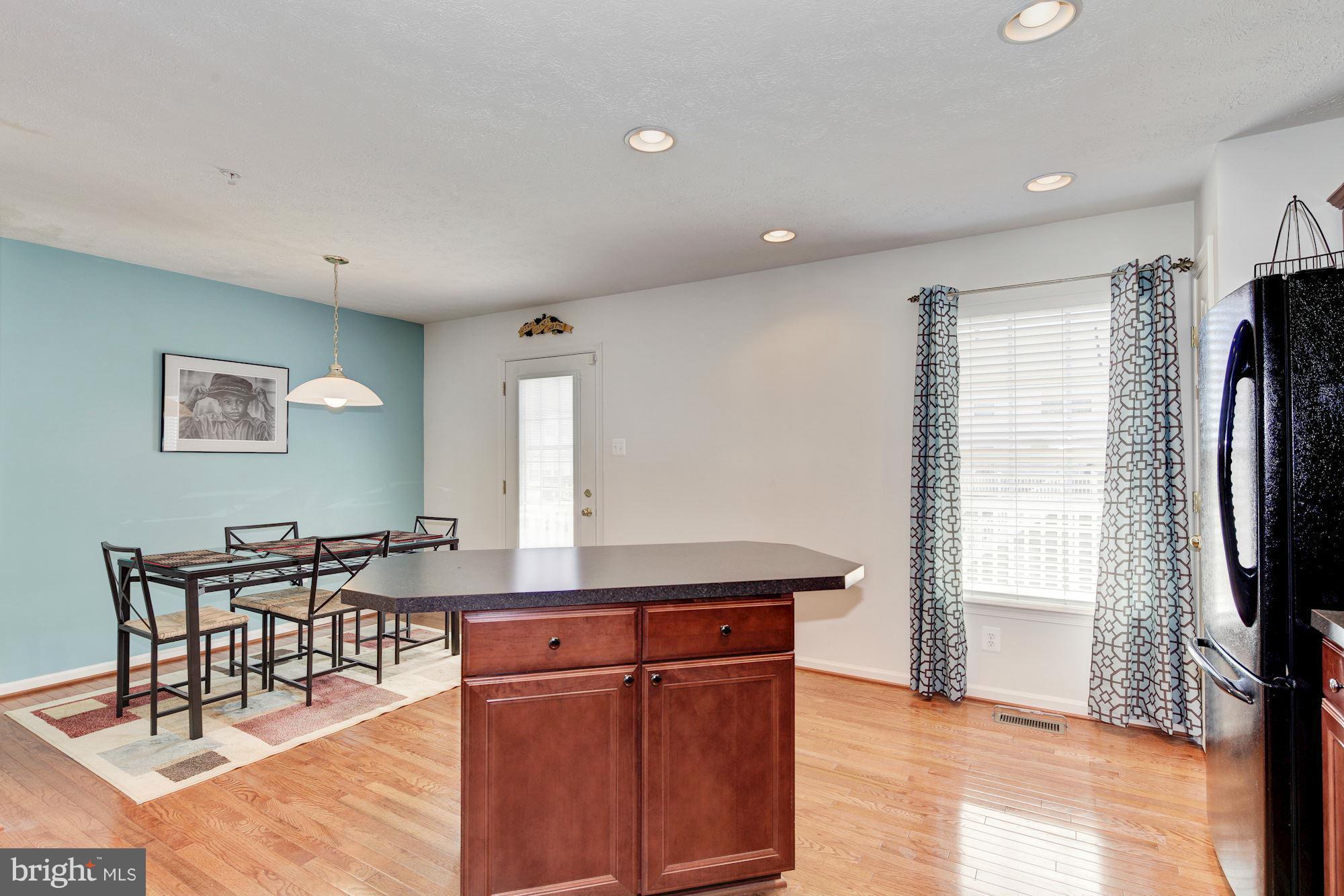 9851 Decatur Road Baltimore, MD 21220 - Photo 13 of 24 a kitchen with stainless steel appliances granite countertop a dining table chairs and a refrigerator