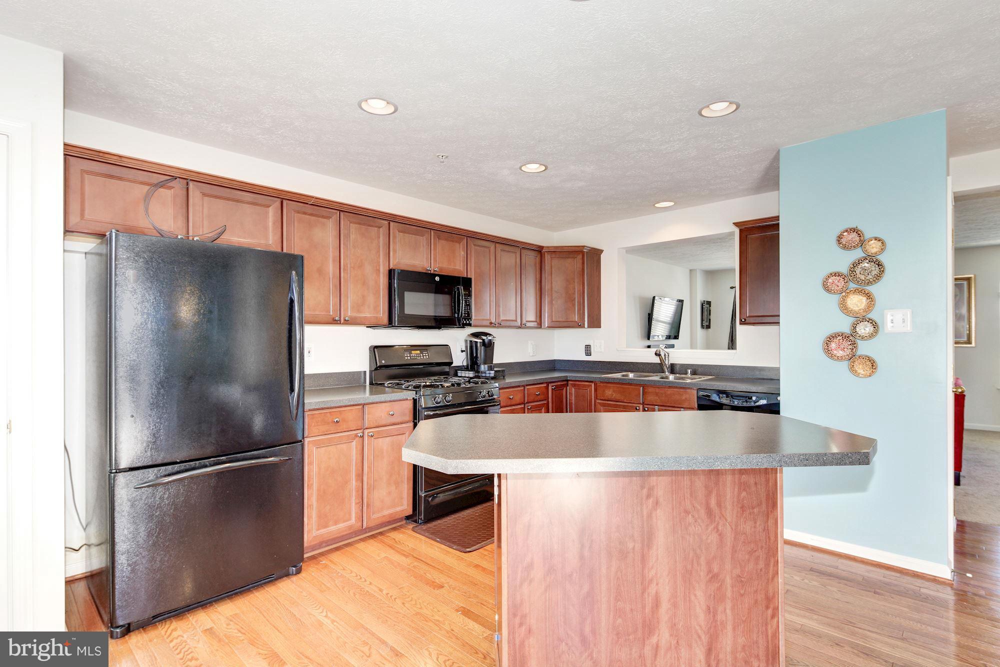 9851 Decatur Road Baltimore, MD 21220 - Photo 9 of 24 a kitchen with stainless steel appliances granite countertop a refrigerator a sink a stove a microwave and island