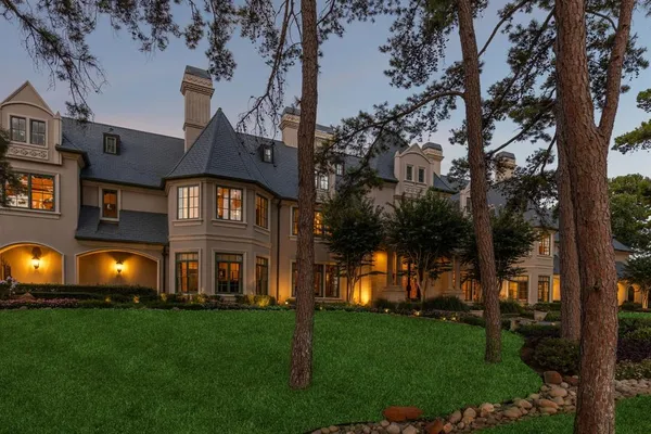 a front view of a house with a big yard and a large tree
