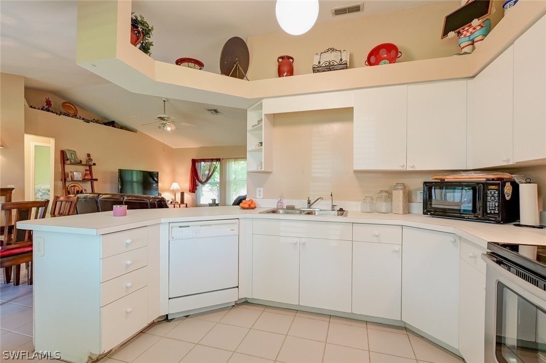 18253 Maple Road Fort Myers, FL 33967 - Photo 11 of 29 a kitchen with white cabinets a sink dishwasher and a stove with wooden floor
