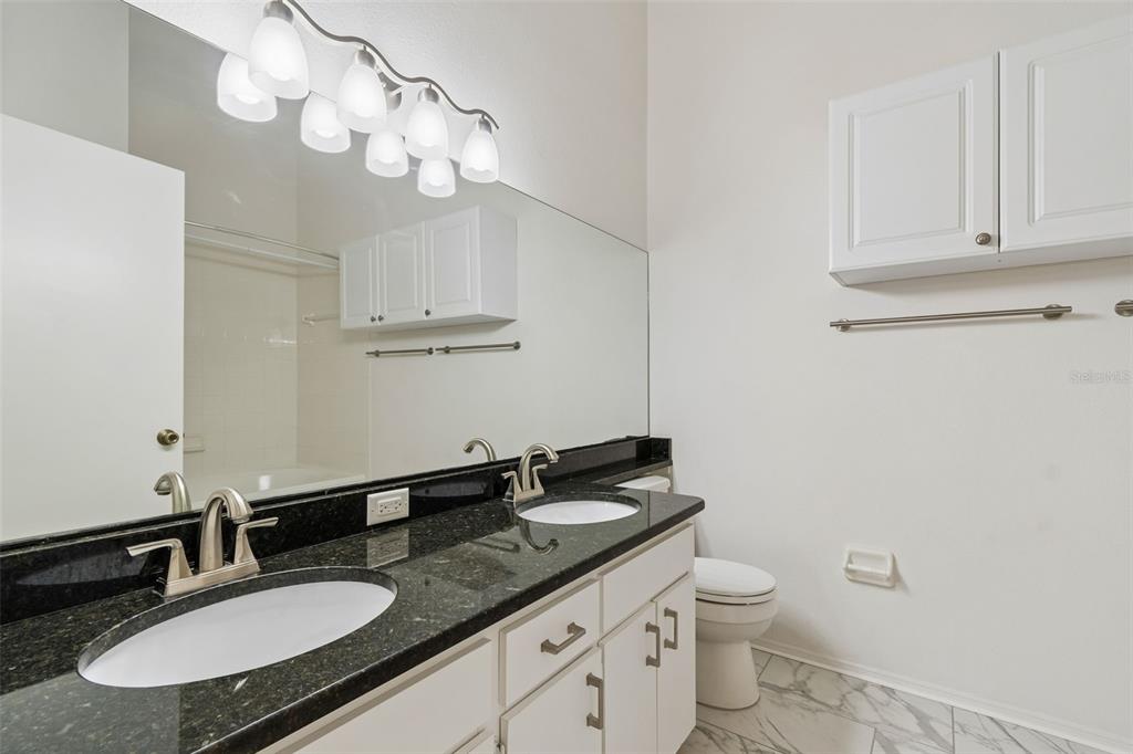 382 Countryside Key Boulevard Oldsmar, FL 34677 - Photo 32 of 58 a bathroom with a granite countertop sink a toilet and a mirror