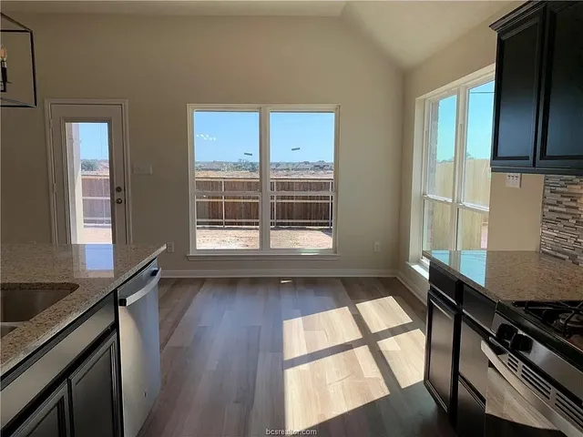 a view of a kitchen with a sink wooden cabinets and a window