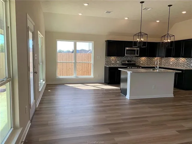a kitchen with stainless steel appliances granite countertop a sink a stove and a wooden floors