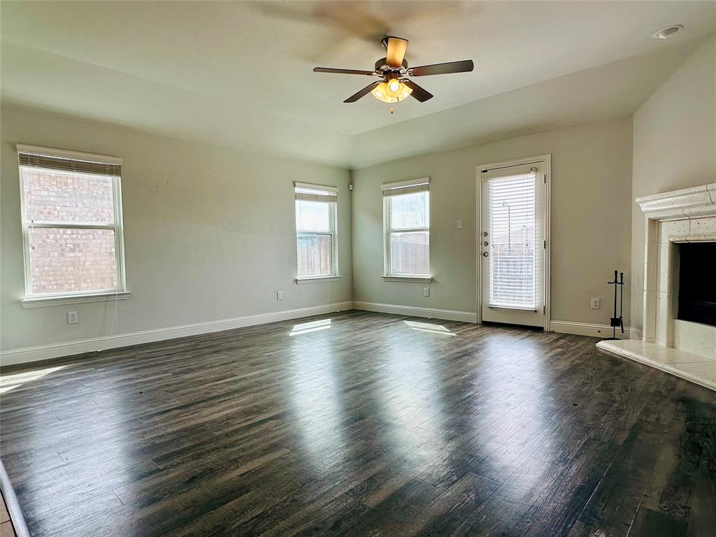 1223 Mount Olive Lane Forney, TX 75126 - Photo 19 of 28 Unfurnished living room with dark wood finished floors, ceiling fan, plenty of natural light, and a fireplace