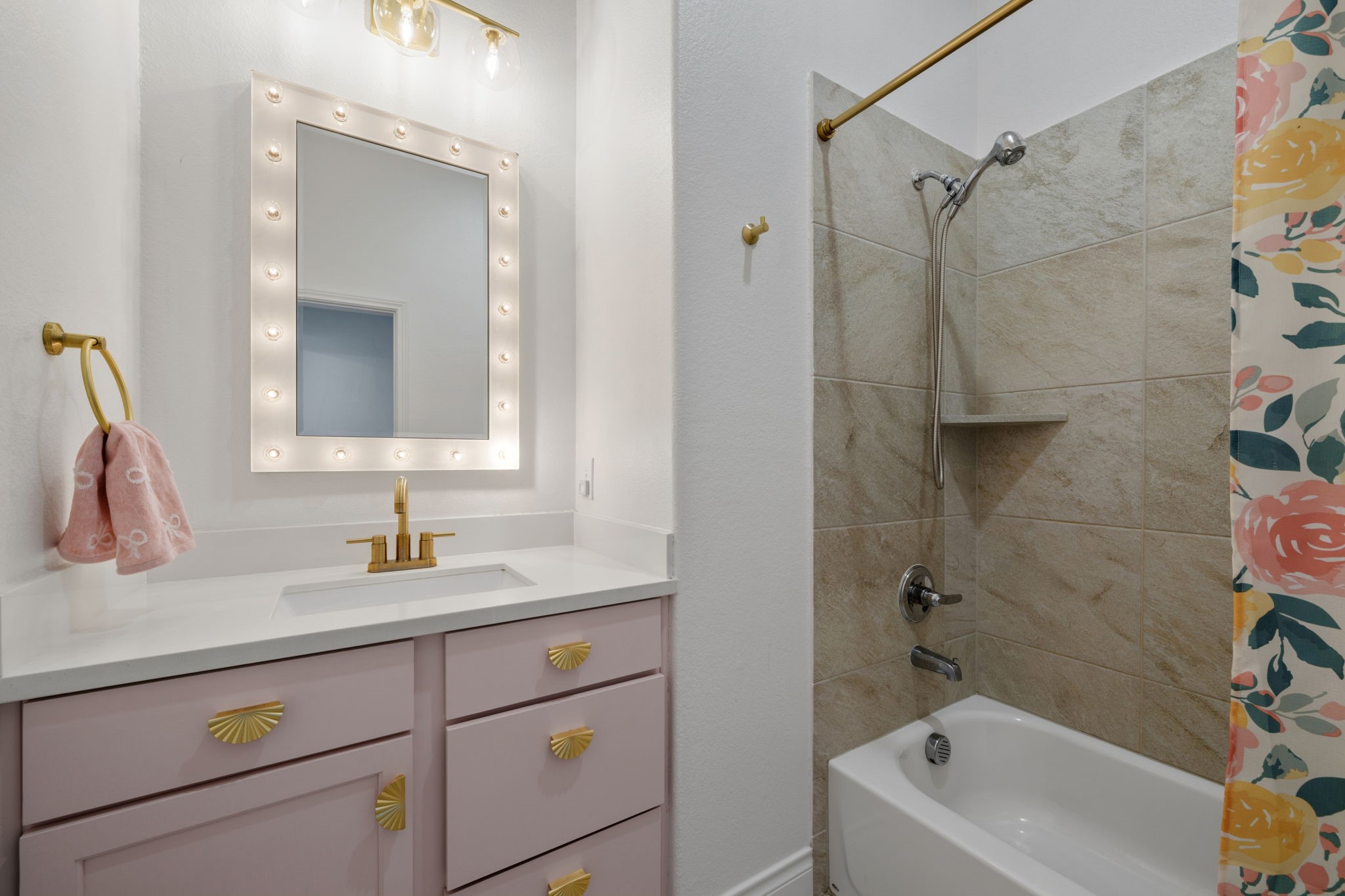 2119 Blackhawk Ridge Lane Manvel, TX 77578 - Photo 27 of 49 Secondary bathroom featuring a custom blush-painted vanity with gold hardware, quartz countertop, Hollywood-style lighted mirror, and a tiled tub/shower combo.