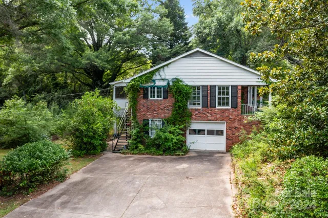 a front view of house with a yard and trees all around