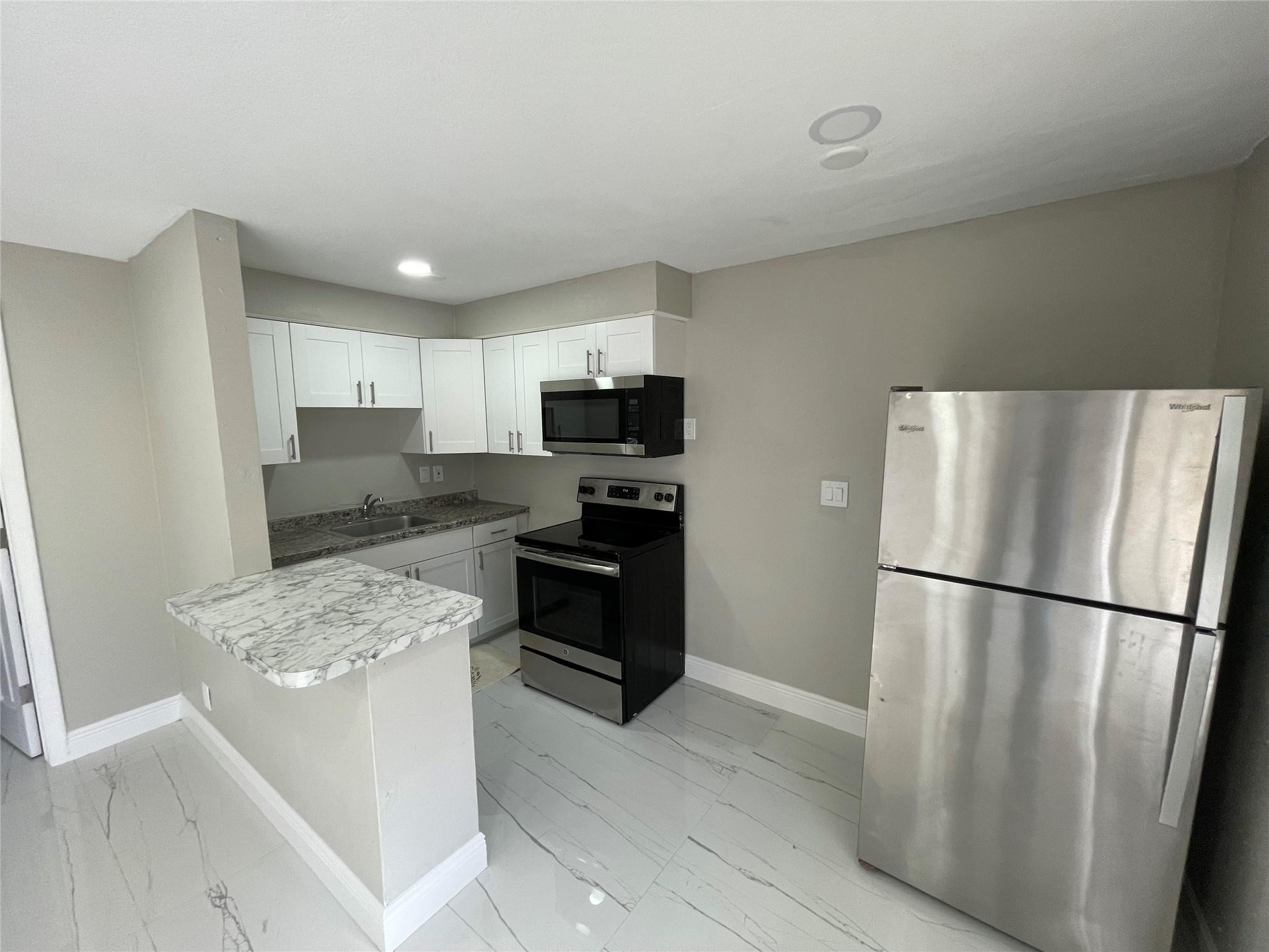 721 Southwest 8th Street Pompano Beach, FL 33060 - Photo 14 of 21 a kitchen with stainless steel appliances granite countertop a refrigerator stove a sink dishwasher and a refrigerator