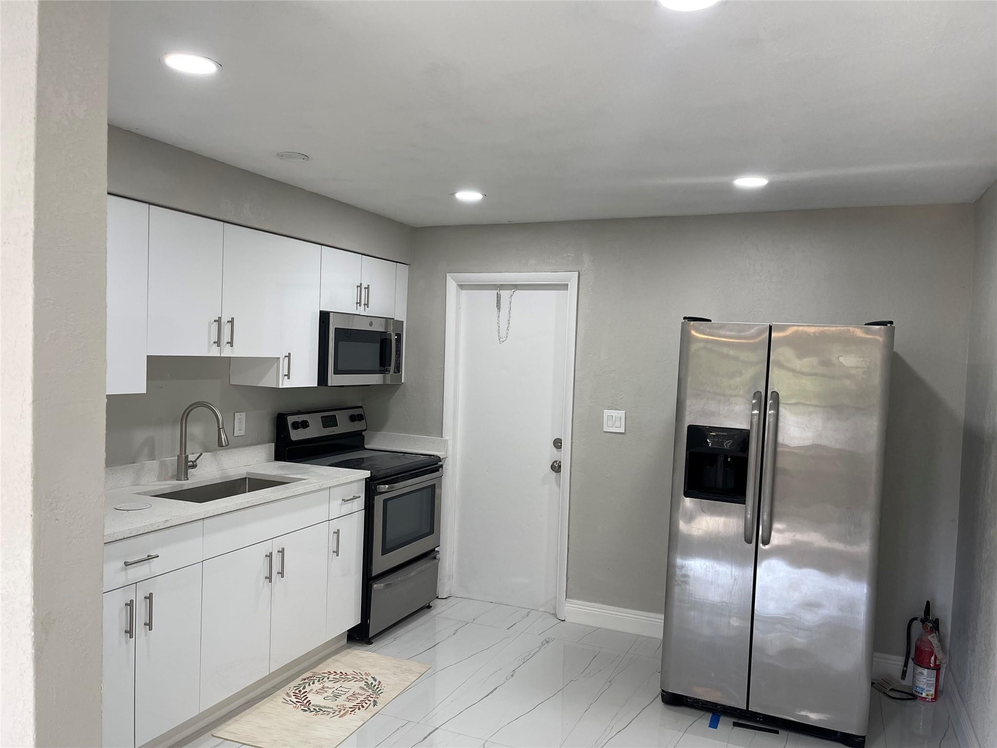 721 Southwest 8th Street Pompano Beach, FL 33060 - Photo 7 of 21 a kitchen with stainless steel appliances granite countertop a refrigerator a sink a stove a microwave and island