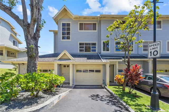 a front view of a house with a yard and a large tree