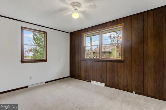 an empty room with windows closet and chandelier fan