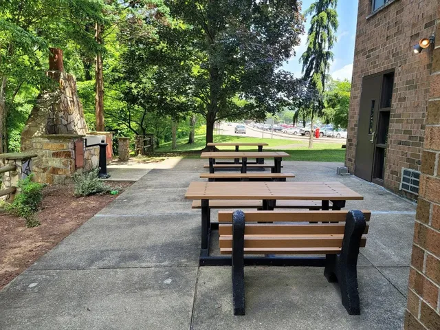 a view of a patio with table and chairs under an umbrella with large trees