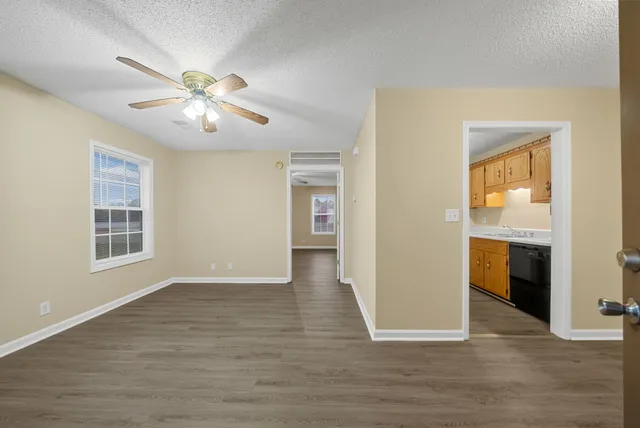 a view of an empty room with a window and wooden floor