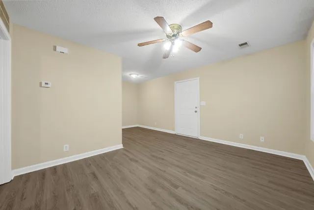 an empty room with wooden floor and windows
