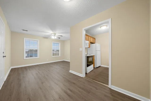 an empty room with wooden floor and windows