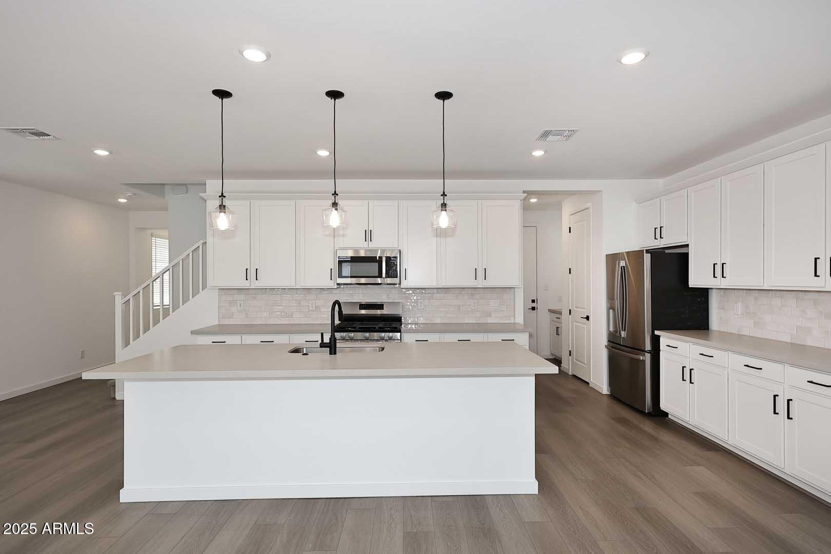 2442 West Rowel Road Phoenix, AZ 85085 - Photo 12 of 55 a large kitchen with stainless steel appliances kitchen island a stove a refrigerator a sink and a oven with wooden floor