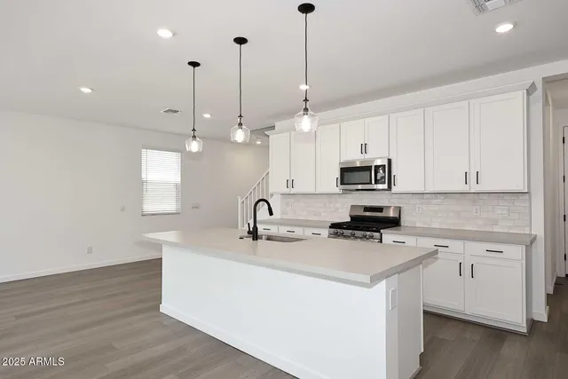 a kitchen with stainless steel appliances kitchen island a white cabinets and wooden floor