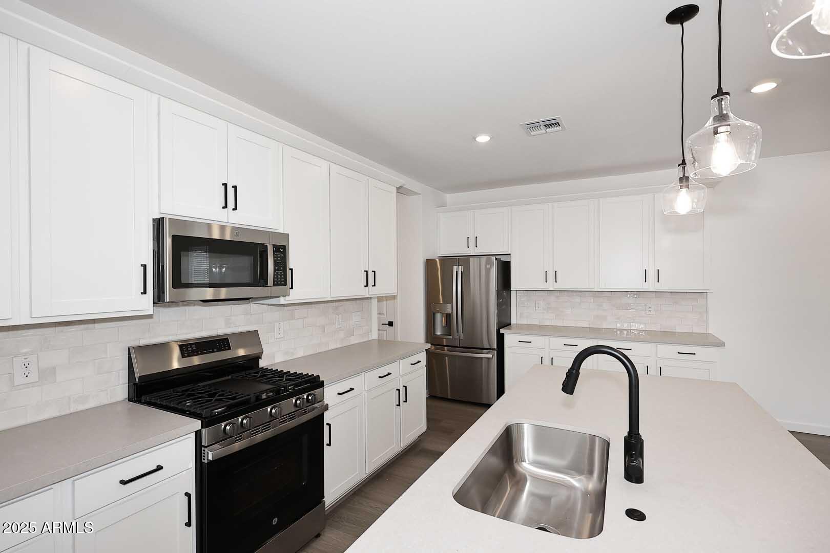 2442 West Rowel Road Phoenix, AZ 85085 - Photo 14 of 55 a kitchen with stainless steel appliances granite countertop a sink a stove a refrigerator and cabinets
